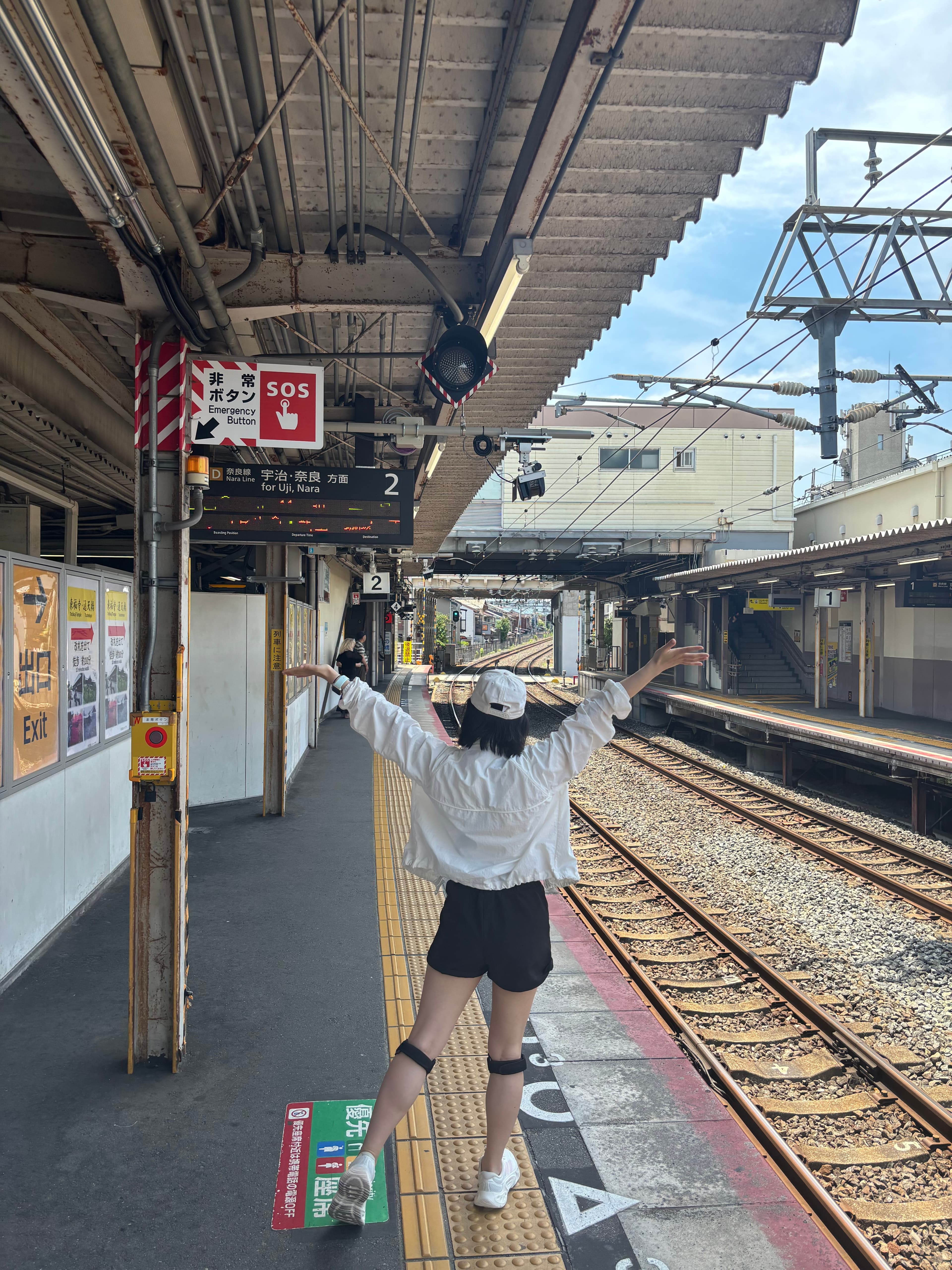 Reina with arms raised on a train station platform